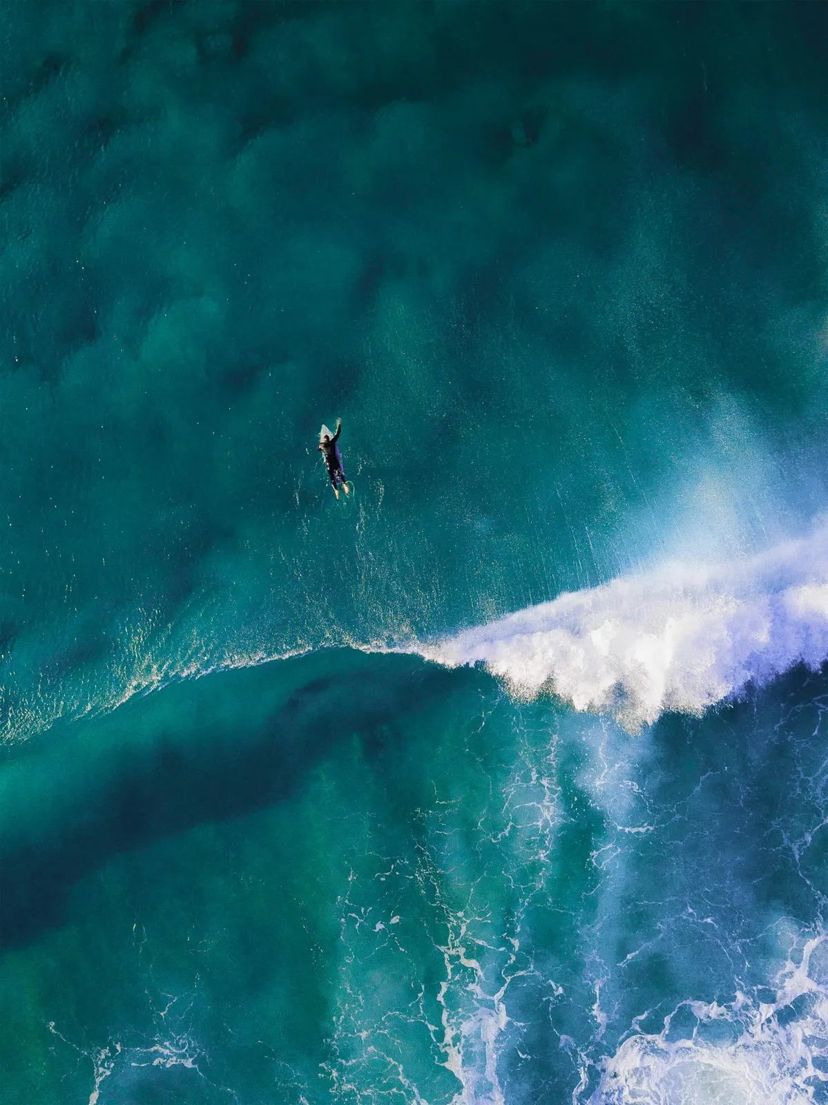 Surfer paddling in turquoise water
